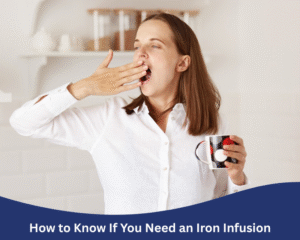 Woman yawning while holding a coffee mug in a bright kitchen, wearing a white shirt, looking sleepy in the morning.